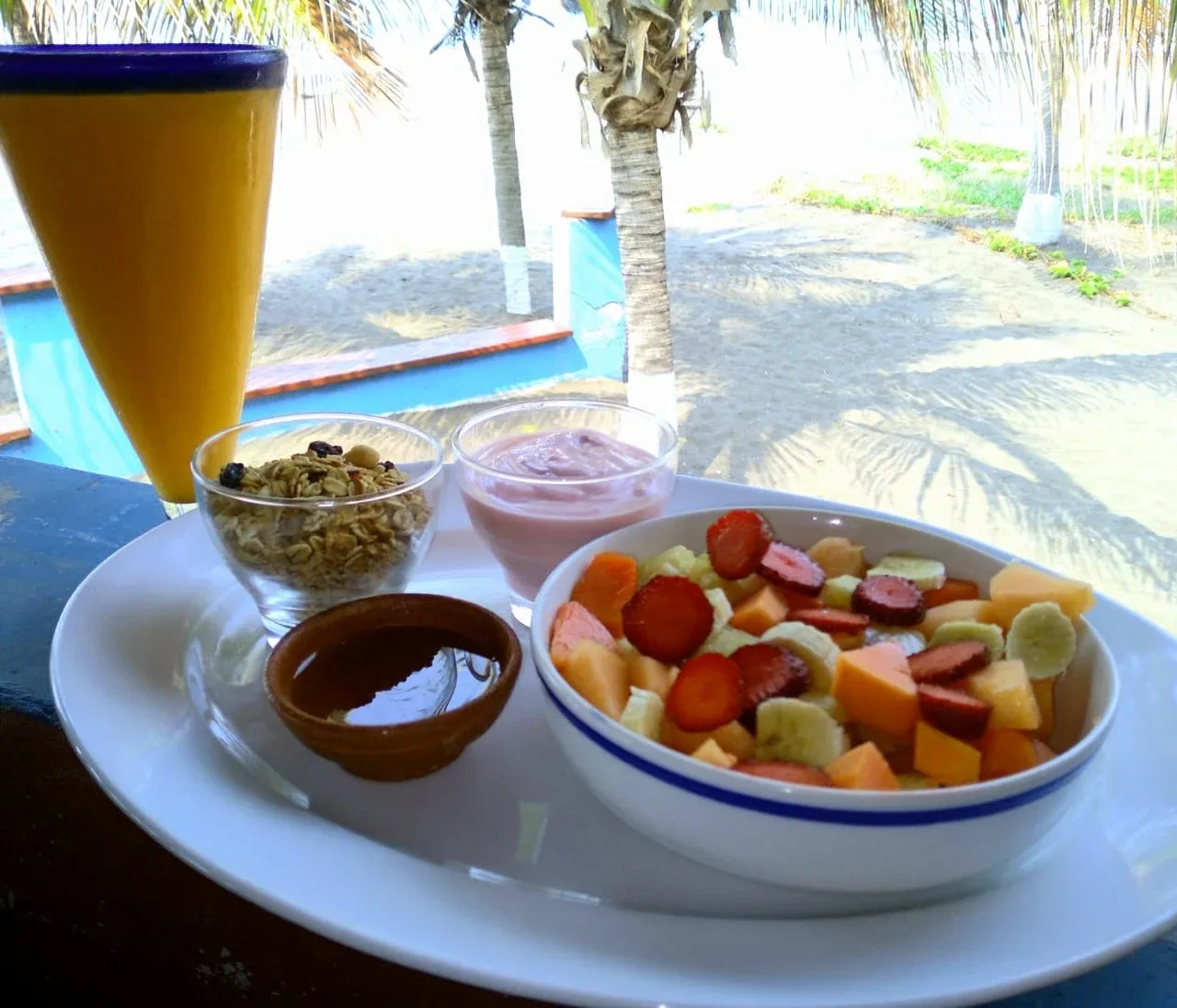 Fruta, yogur y granola servidos en una mesa frente a la playa